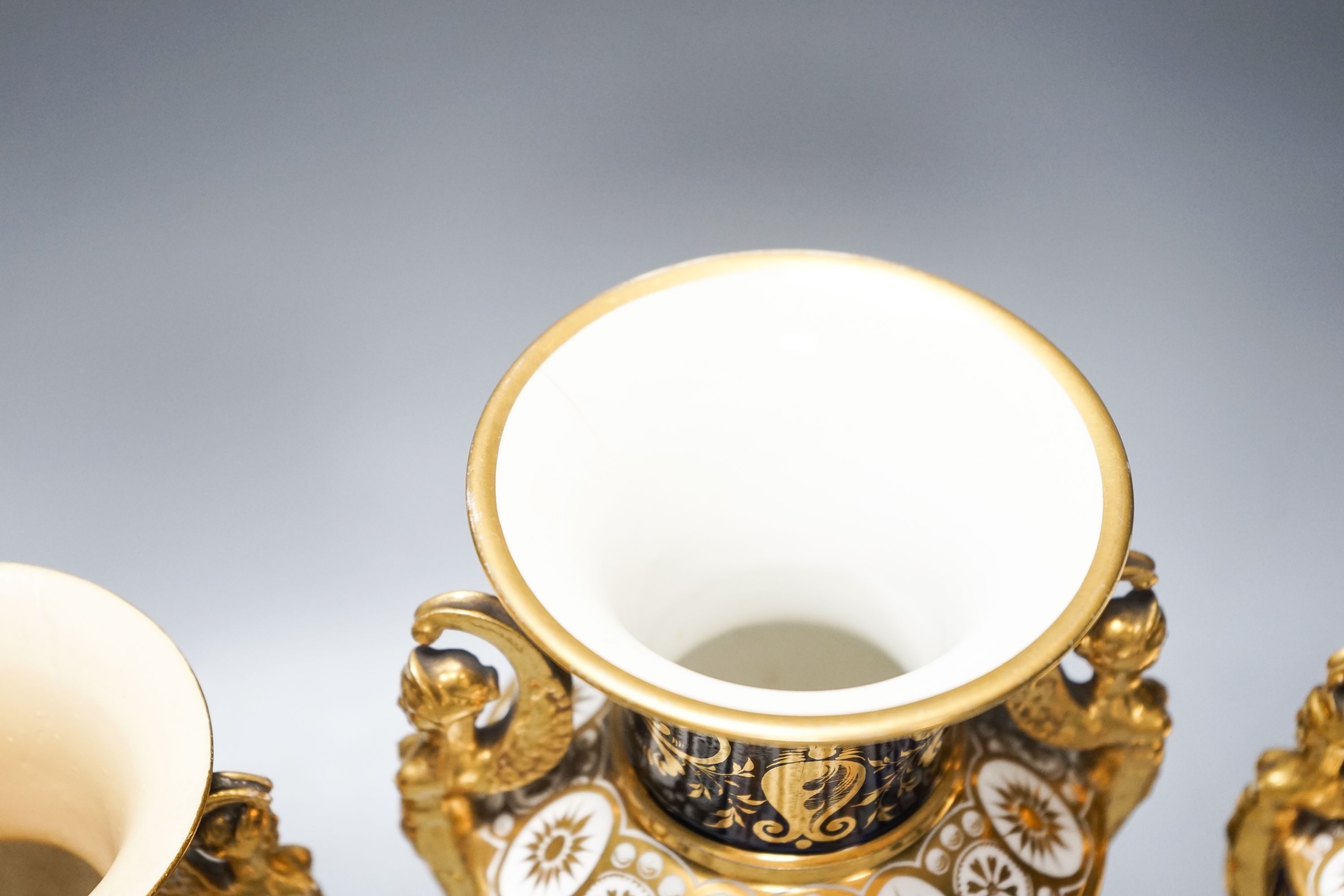 A garniture of three early 19th century English porcelain vases, c.1815-20, each painted with topographical views, tallest 26cm